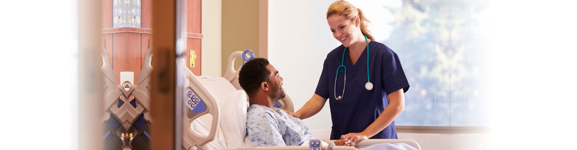 Female Doctor Talking To Male Patient In Hospital Bed