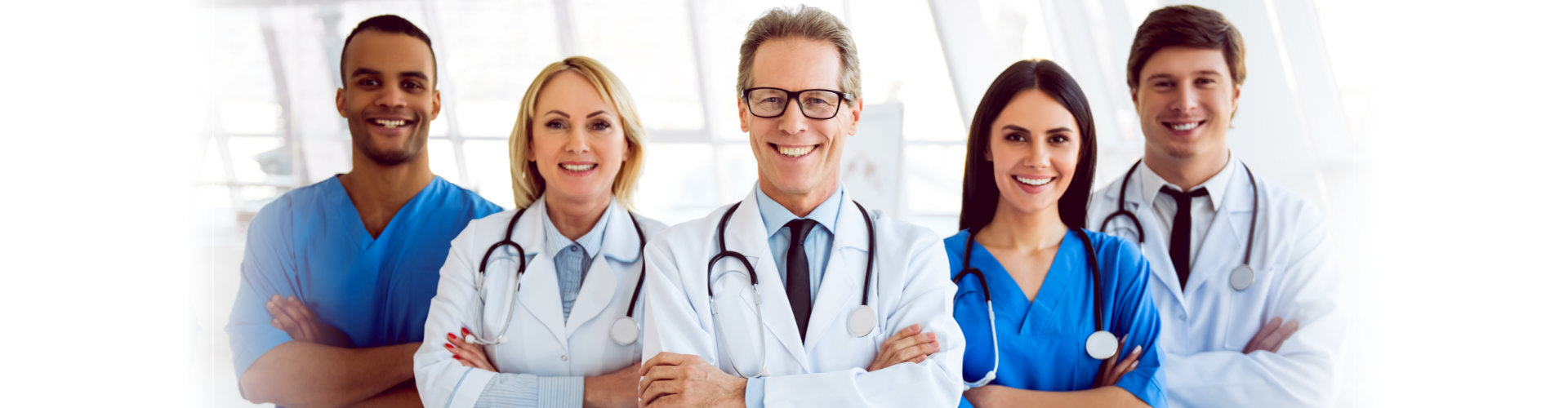 Successful team of medical doctors are looking at camera and smiling while standing in hospital